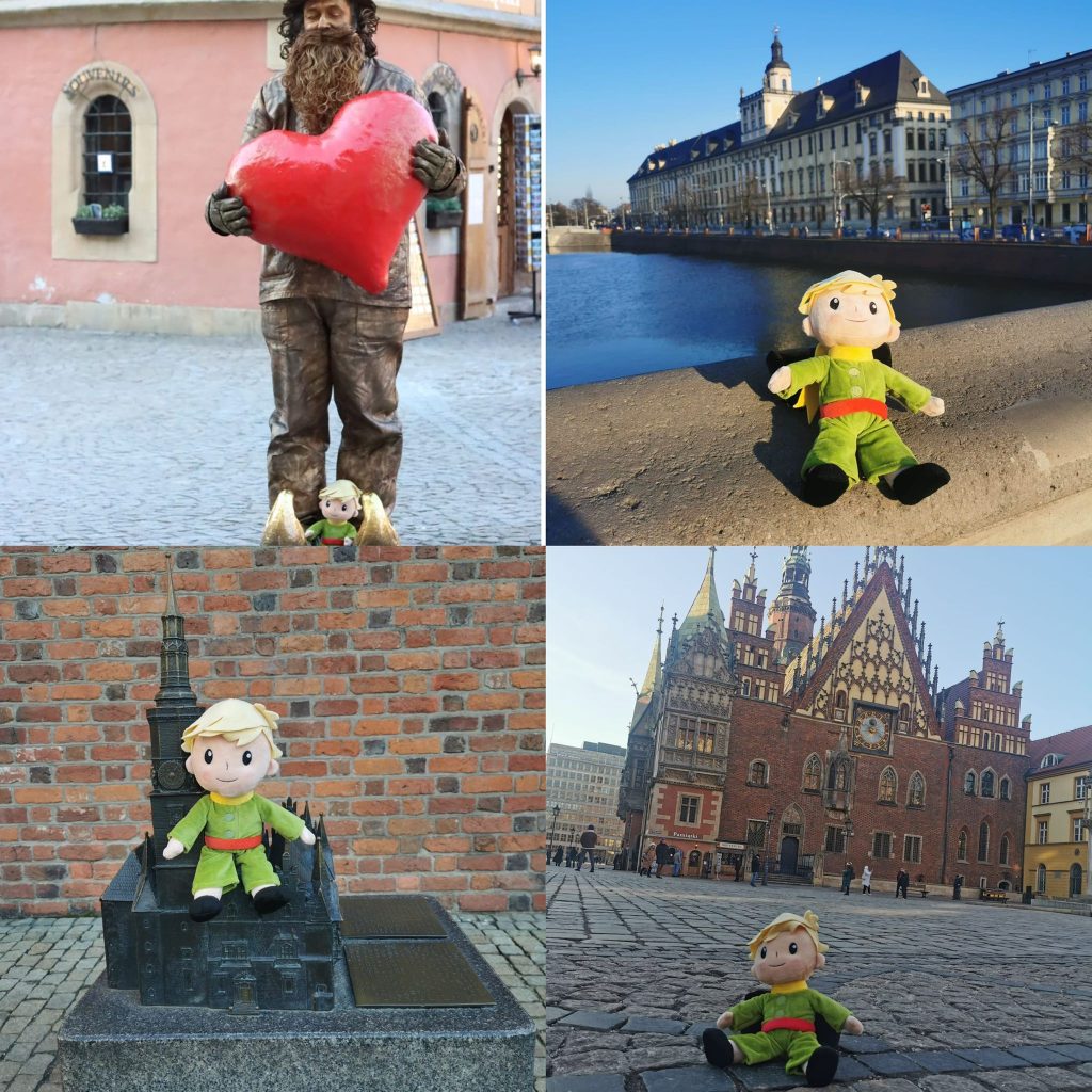 Cztery zdjęcia przedstawiające postać Małego Księcia w różnych miejscach. Na pierwszym zdjęciu maskotka Mały Książę siedzi u stóp wysokiej brodatej postaci, trzymającej duże czerwone serce. W tle kamienica w jasnoróżowym odcieniu. Na drugim zdjęciu Mały Książę siedzi na balustradzie mostu. Za nim rzeka i Uniwersytet Wrocławski. Na trzecim zdjęciu Mały Książę siedzi na makiecie kościoła. W tle ceglasta ściana. Na czwartym Mały Książę siedzi na kamiennym bruku rynku wrocławskiego. W tle wrocławski ratusz. Postać Małego Księcia ma jasne włosy, ubrana jest w zielony kombinezon i czerwony pasek.